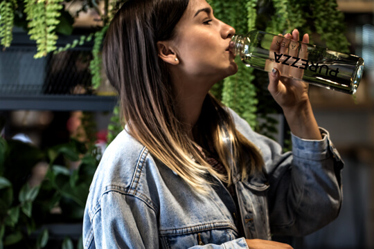 Lady drinking water from her purezza glass drinking bottle